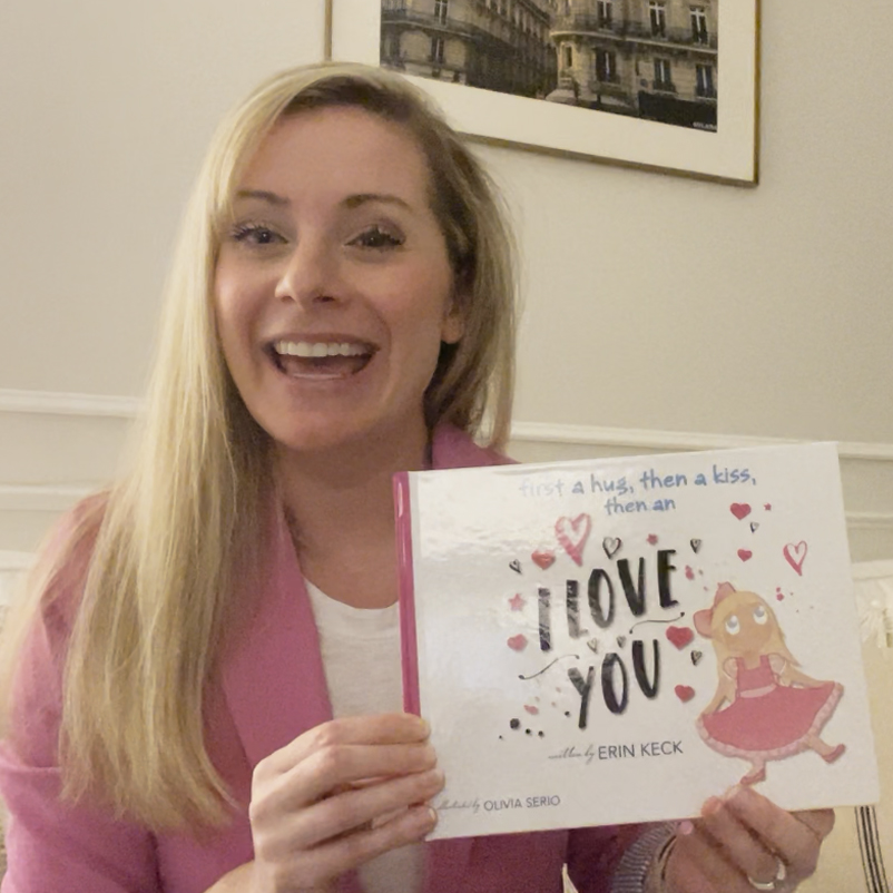 Picture of author Erin Keck holding her book "First a Hug, then kiss, then an I love you."