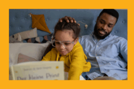 A young Black girl wearing glasses and a yellow hoodie excitedly reads a book titled Der kleine Prinz in bed, while her smiling father sits beside her and gently pats her head. The background shows a cozy bedroom with pillows and a wall-mounted kite decoration.