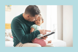 Father reading a book to his toddler daughter while sitting on a bed in a bright room, fostering early literacy and bonding.