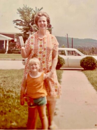 A childhood photo of a mother and her daughter smiling on the front yard