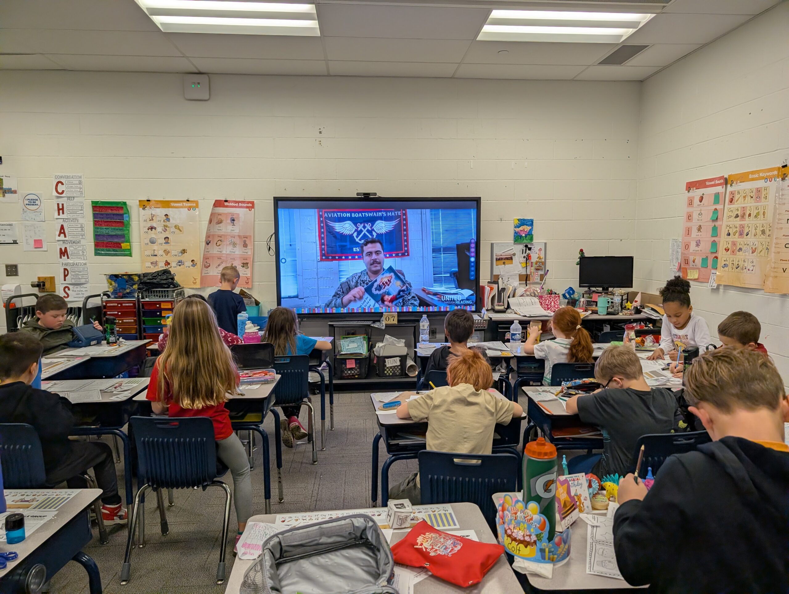 Photo of children writing letters to service members while watching a storytime video.