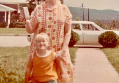 A childhood photo of a mother and her daughter smiling on the front yard